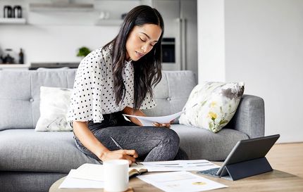 A woman paying her bills and taking notes.