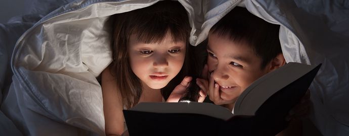 Two kids with a flashlight during a power outage.