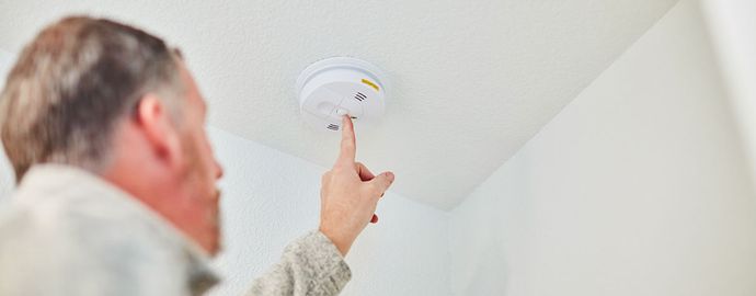 A man testing a smoke detector.