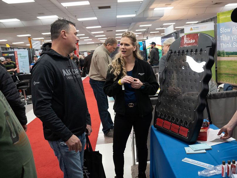 Un agriculteur joue au « Plinko de la sécurité » avec un membre de l’équipe de sécurité publique d’Hydro Manitoba au kiosque de la Société lors des journées agricoles.