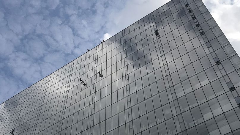 Two individuals in safety harnesses on exterior wall of building.