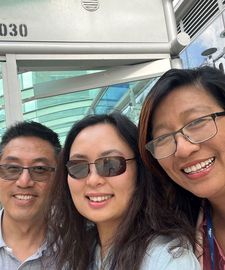 Three people pose for a selfie in front of a bus shelter.