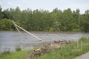 A hydro pole is tipping into floodwaters.