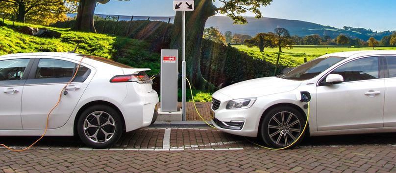 Deux véhicules électriques sont stationnés sur une rue ensoleillée.