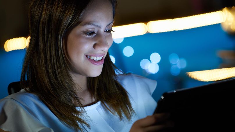 A person looking at a computer screen and smiling.