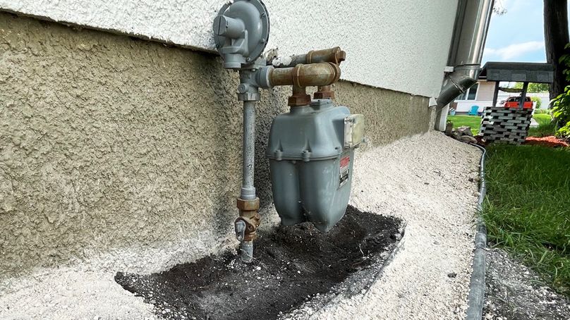 A close-up photo of a natural gas meter with dirt excavated around it and surrounded by fresh gravel and landscaping.