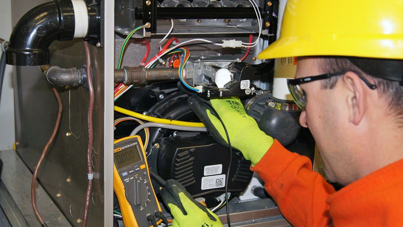 Male service person inspects a furnace.