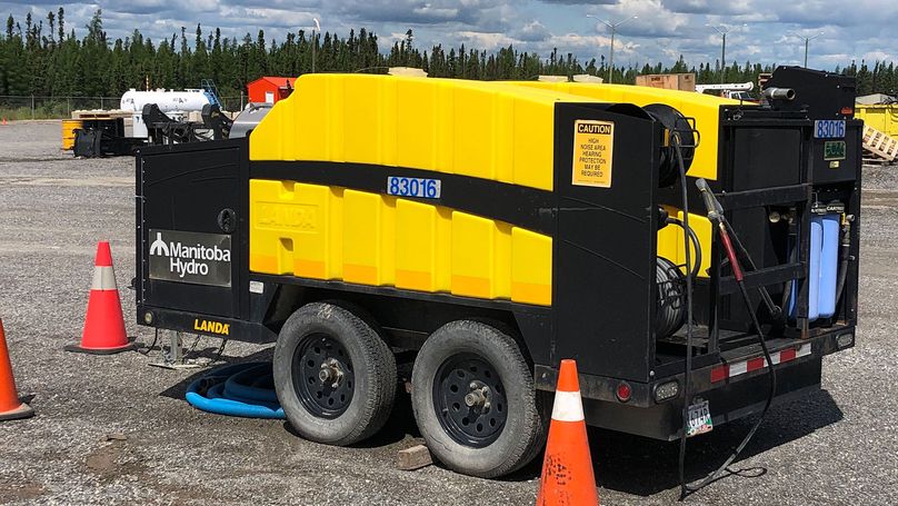 Une remorque en métal noir dotée d’une chambre en plastique jaune servant à contenir le liquide de décontamination ainsi que de plusieurs pulvérisateurs à haute pression.